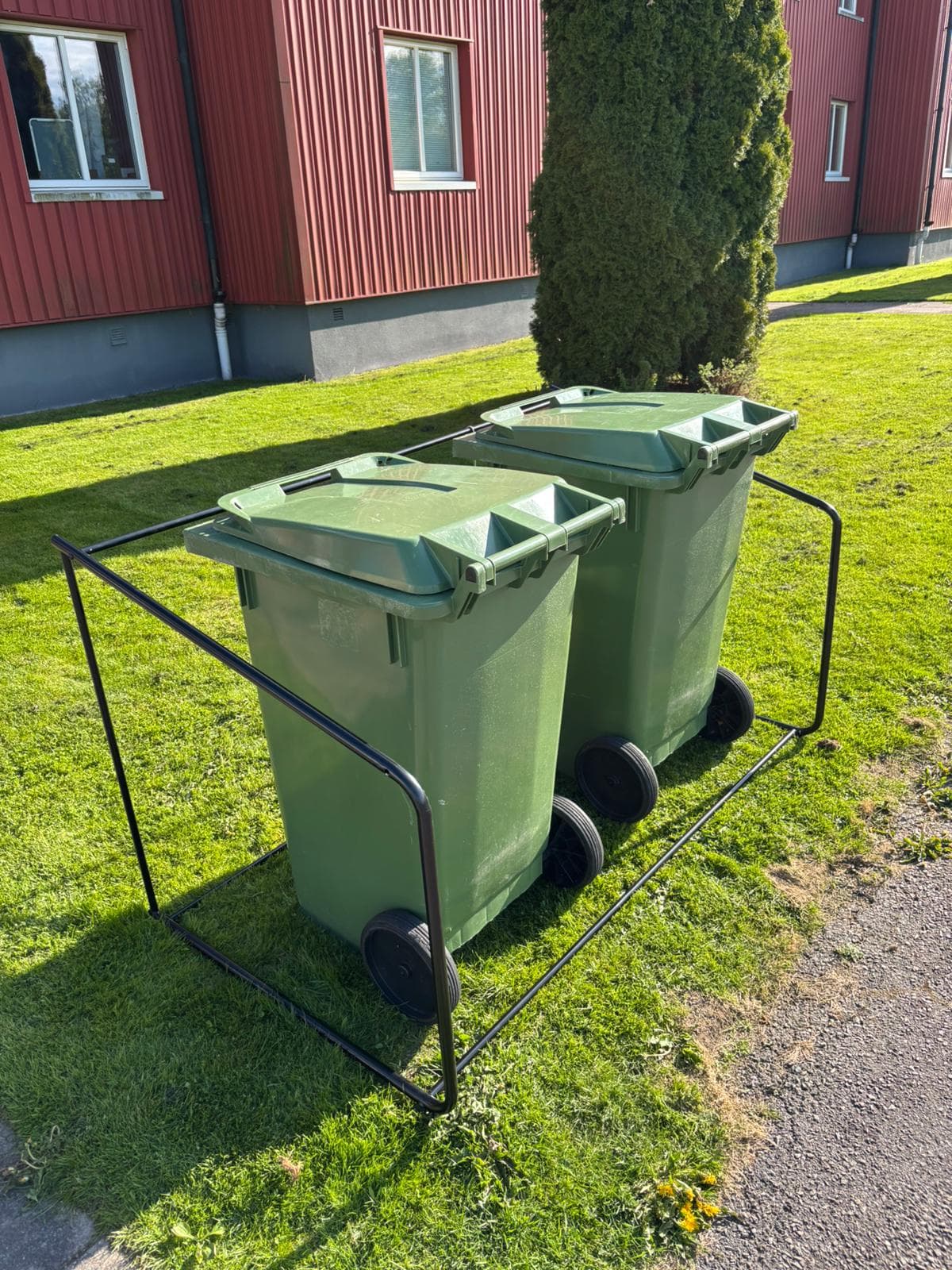 Semachs öppna soptunnegarage uppställt på en gräsmatta utanför ett rött radhus