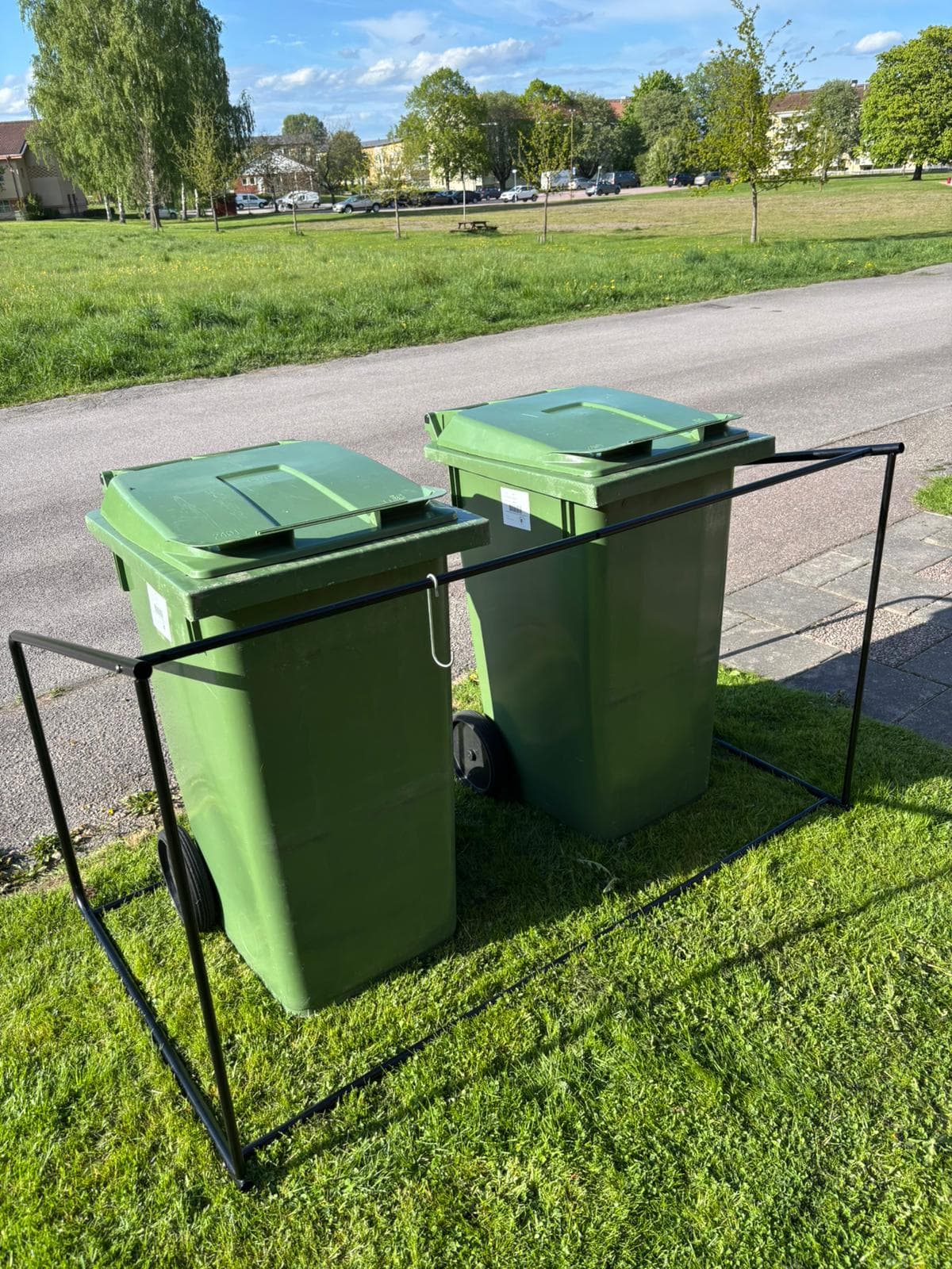 Semachs öppna soptunnegarage uppställt på gräset intill en bilväg