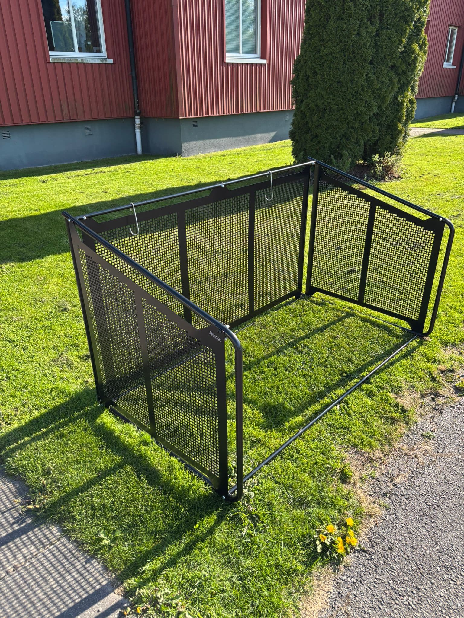Tomt Semach soptunnegarage med täcksidor uppställt på en gräsmatta utanför ett rött radhus
