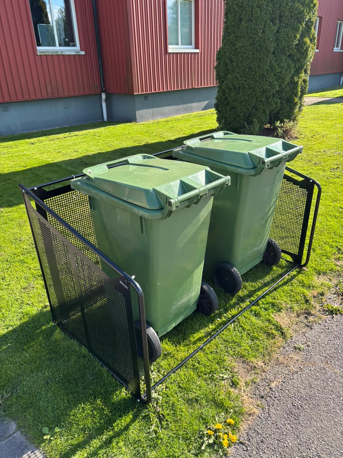 Semachs soptunnegarage med täcksidor och två gröna soptunnor utanför en villa
